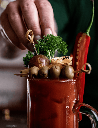 Bloody Mary cocktail decorated with olives, chillies, parsley and other toppings