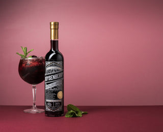 Boysenberry Liqueur with a pink background and a cocktail with mint leaves