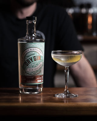 Simple dry martini with a lemon twist garnish presented alongside a bottle of Delightful Dry Gin