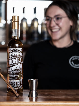 Isabella smiling in the background of a honey liqueur bottle shot