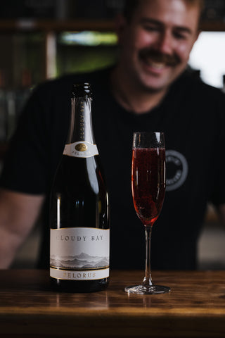 Jeremy smiling in the background of the Kir Royal boysenberry cocktail