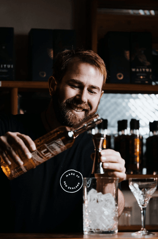 Jeremy pouring a shot of Lime Liqueur in a dark bar