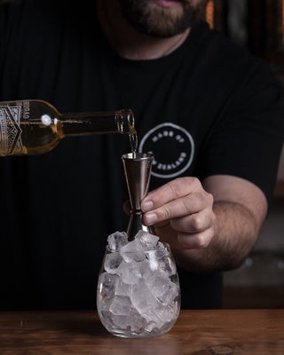 Ruby Tuesday with a glass filled with ice pouring the tangelo liqueur