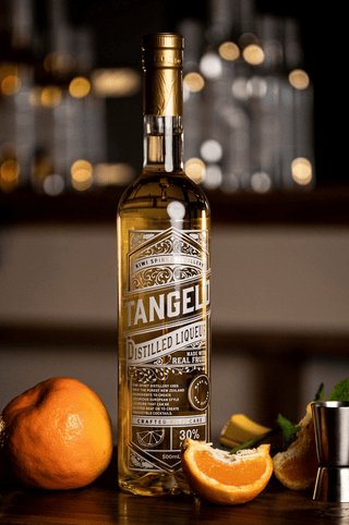 Tangelo Liqueur bottle on wooden bar with fresh cut tangelos