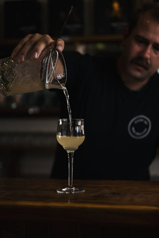 Poured finished cocktail into goblet glass on wooden bar