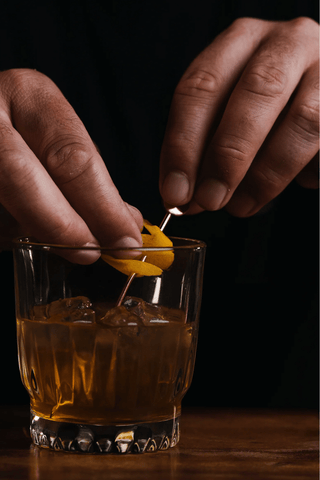Golden honey cocktail in a short glass with orange garnish