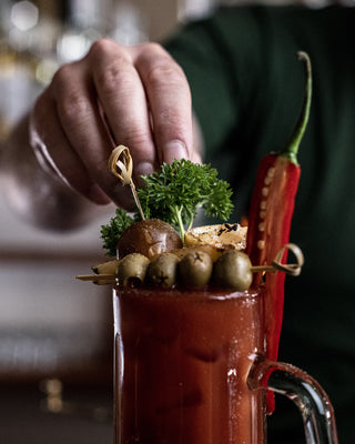 Bloody Mary cocktail decorated with olives, chillies, parsley and other toppings