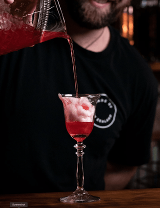 Jeremy pouring Cotton Candy Brandy into a glass with cotton candy melting as the liquid is poured onto it