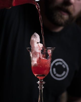 Jeremy pouring Cotton Candy Brandy into a glass with cotton candy melting as the liquid is poured onto it