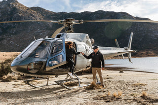 Person stepping out of a helicopter at Kahurangi National Park lake