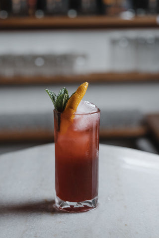 Spring Punch on a marble bar, ruby red drink with mint and orange peel