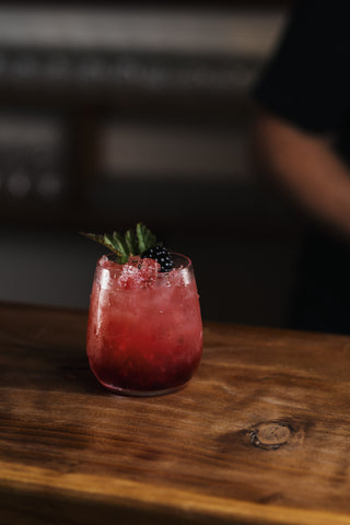 Marbled bramble cocktail presented in a short round glass and garnished with mint and boysenberries