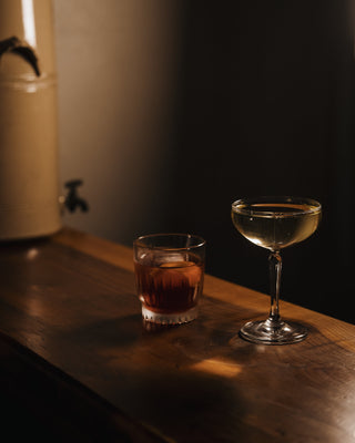 Two cocktails on a dark wooden bar