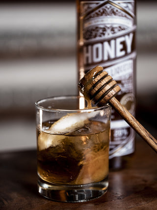 Honey Liqueur with honey slowly dripping into a glass of Honey Liqueur