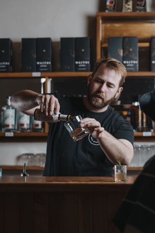 Jeremy behind the bar at the cellar door making a sample drink for a customer