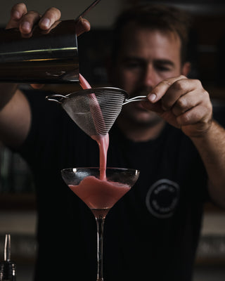 Jeremy pouring pink Clover Club cocktail from a shaker into a martini glass