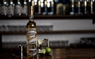 Lime Liqueur with fresh limes and a mixer on the wooden bar