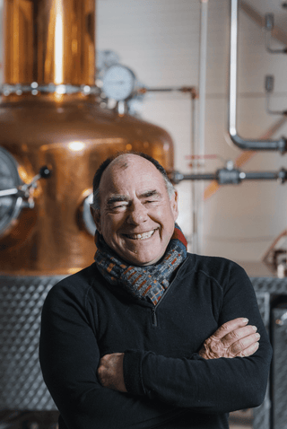 Founder Terry smiling in front of copper stills