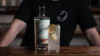 Tom Collins and Delightful Dry Gin bottle on the bar